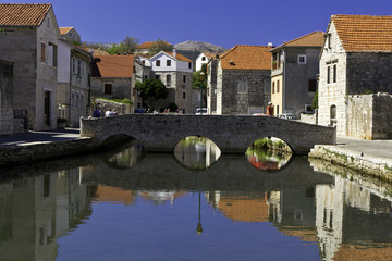 Fototapeta na wymiar Unidentifiable tourists on the old bridge in the 15th century village of Vrboska, in Croatia