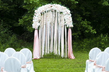 White chairs stand in the rows before wedding altar in park