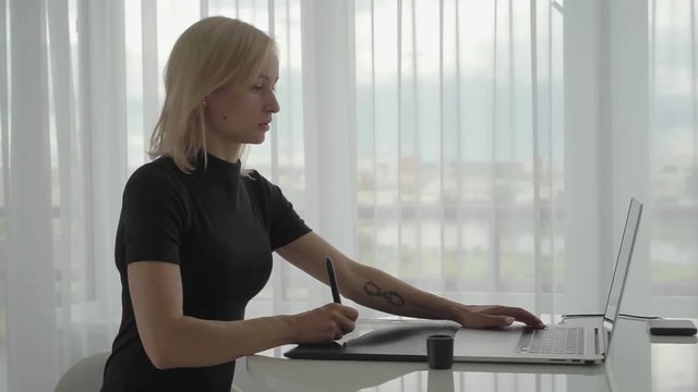 Woman designer draws on a graphics tablet. Woman working with laptop in office