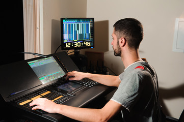 A lighting engineer works with lights technicians control on the concert show. Professional light...