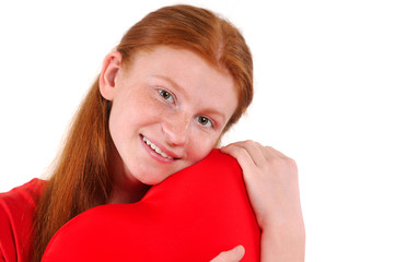 Young red hair girl tenderly hug a heart shape on white background