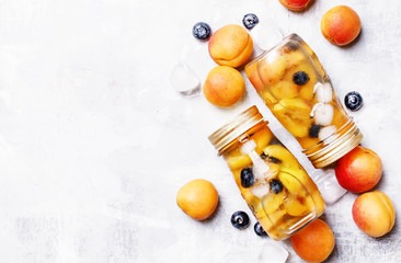 Summer fruit drink with apricot, blueberry and ice, food background, top view