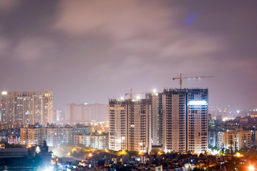 Skyscraper being built in the middle of the city of Noida, Delhi. The construction cranes are clearly visible atop the half finished structure of the building