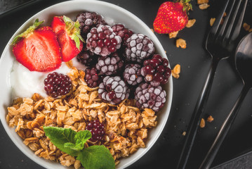 Healthy breakfast. Summer berries and fruits. Homemade Greek yogurt with granola, blackberries, strawberries and mint. On a black stone table, with the ingredients.