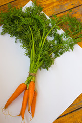 Bundle of carrots on  white and wooden background. Top view