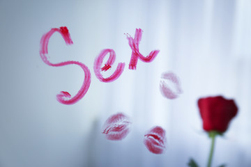 Word SEX written with red lipstick on mirror