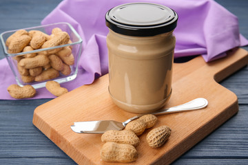Jar with creamy peanut butter on table