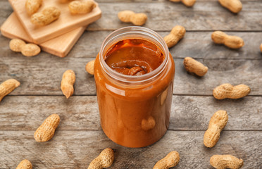 Jar with creamy peanut butter on table