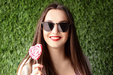 Beautiful young woman with bright lips on green grass background