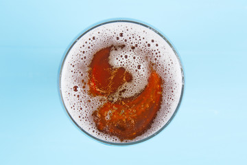 Beer in glass. Beer foam. View from above on blue background