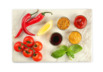 Marble board with different sauces and vegetables on white background