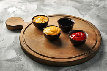 Wooden board with different sauces on grunge background