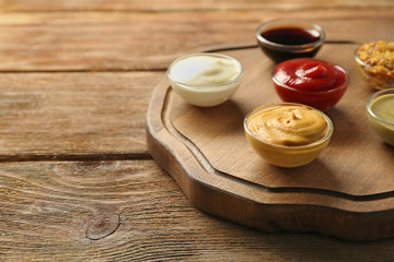 Wooden plate with different sauces on table