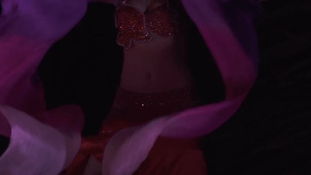 Beautiful belly dancer, night. Beautiful young woman belly dancer dancing belly movement, modern, on black background, slow motion. Close up.