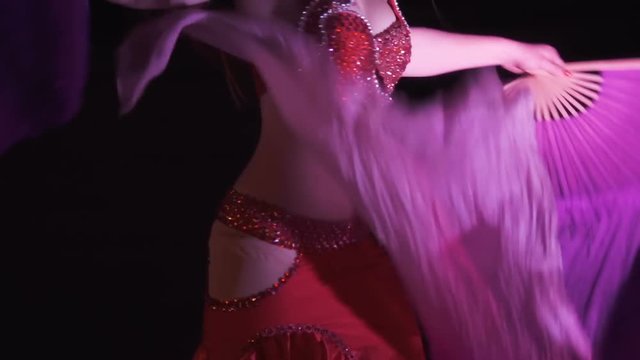 Beautiful belly dancer, night. Beautiful young woman belly dancer dancing belly movement, modern, on black background, slow motion. Close up.