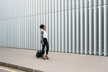 Front view of beautiful woman with luggage walking outside