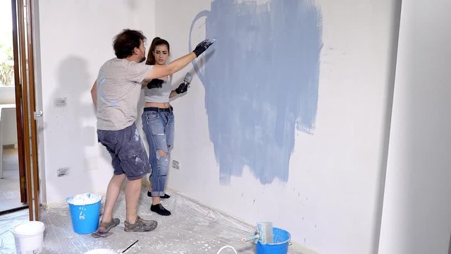 Man getting angry with girlfriend painting wall