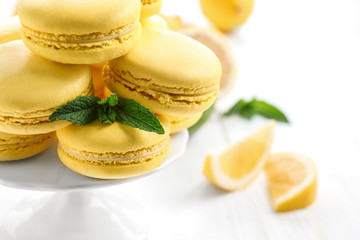 Stand with tasty lemon macarons on light table, closeup