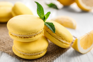 Tasty lemon macarons on white wooden table, closeup