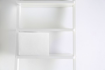 Book with blank white cover on shelf