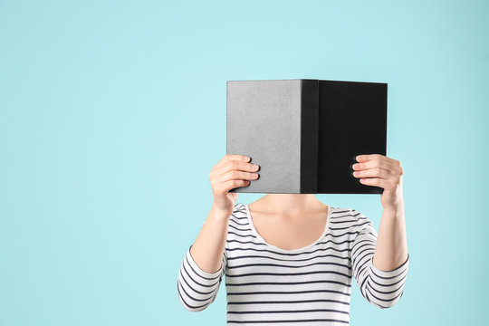 Woman Holding Open Book With Blank Black Cover On Color Background