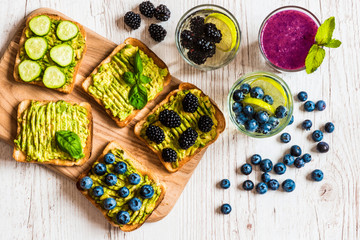Set of vegetarian toast sandwiches with avocado and drinks. Variety of healthy food and drinks on white wooden background