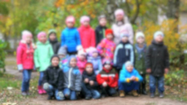 Blurred video. Little children dressed in jacket posing for photos in kindergarten outdoors in autumn