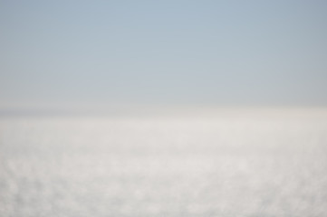 Blurry light on the water textured background. Sunny outdoors seascape bright surface