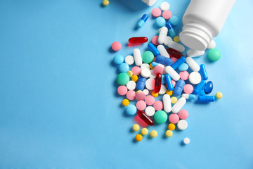 Plastic container and different pills on color background