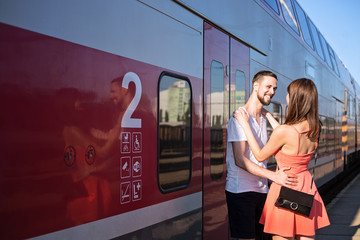 Happiness of  young caucasian couple seeing each for the first time. They are standing next to the train, wearing casual summer clothes.