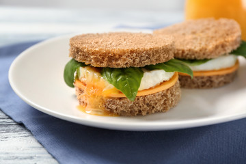 Delicious sandwiches with over easy egg,  cheese and basil leaves on kitchen table