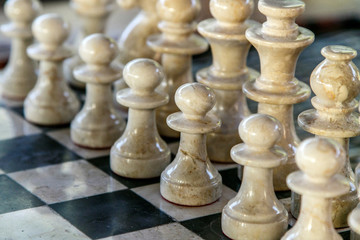 Stone carved chess pieces on chessboard.