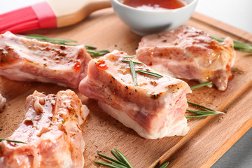 Pork ribs and rosemary on wooden board, closeup