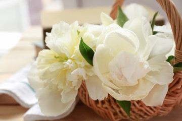 Wicker basket with beautiful peony flowers on table