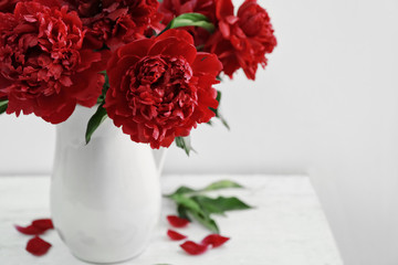 Vase with beautiful peony flowers on table