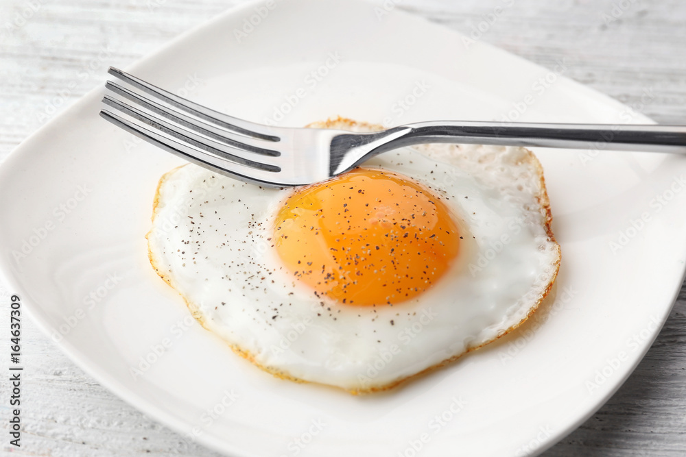 Wall mural plate with sunny side up fried egg on wooden table