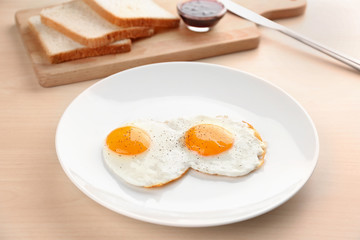 Composition with sunny side up fried eggs, bread and jam on wooden table
