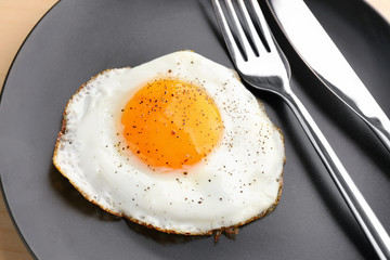 Sunny side up fried egg with fork and knife on plate