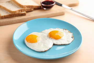 Composition with sunny side up fried eggs, bread and jam on wooden table