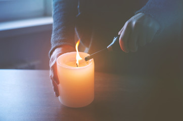 hand lighting candle in evening