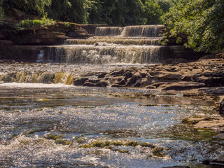 Obraz premium The Lower Falls, Aysgarth waterfalls on beautiful summers day at Aysgarth, Leyburn, North Yorkshire, UK