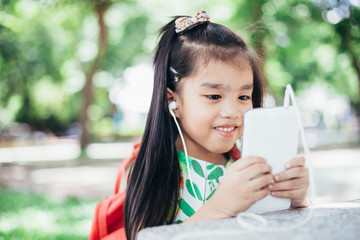 Happy Asian girl playing game on mobile phone