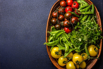 Red and yellow tomatoes, watercress salad and green pea on try. Harvest or clean healthy eating concept. Top view.