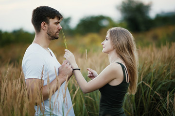 Fototapeta premium Romantic Couple at Sunset. Two people in love at sunset or sunrise. Man and woman on field