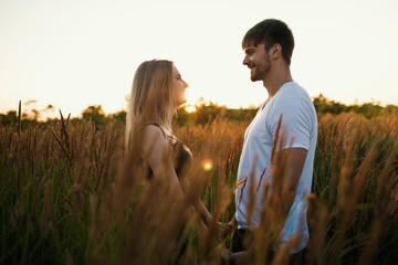 Romantic Couple at Sunset. Two people in love at sunset or sunrise. Man and woman on field