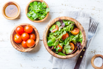Vegetarian salad with lettuce and tomatoes in olive wooden bowl