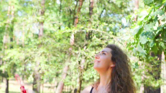 Beautiful young woman play with soap bubbles on nature