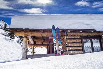 Poster Verschneite Hütte mit Ski in den Alpen © mmphoto
