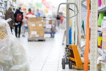 Cargo trolley of orange colour near goods shelves in supermarket