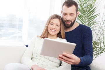 Cheerful young couple working on digital tablet.